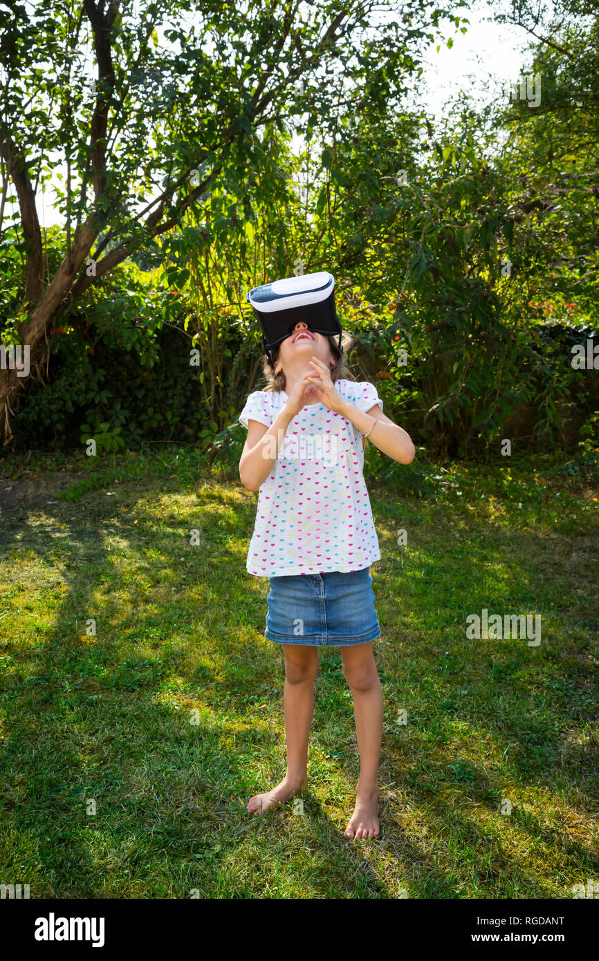 Bambina indossa occhiali per realtà virtuale in giardino Foto Stock