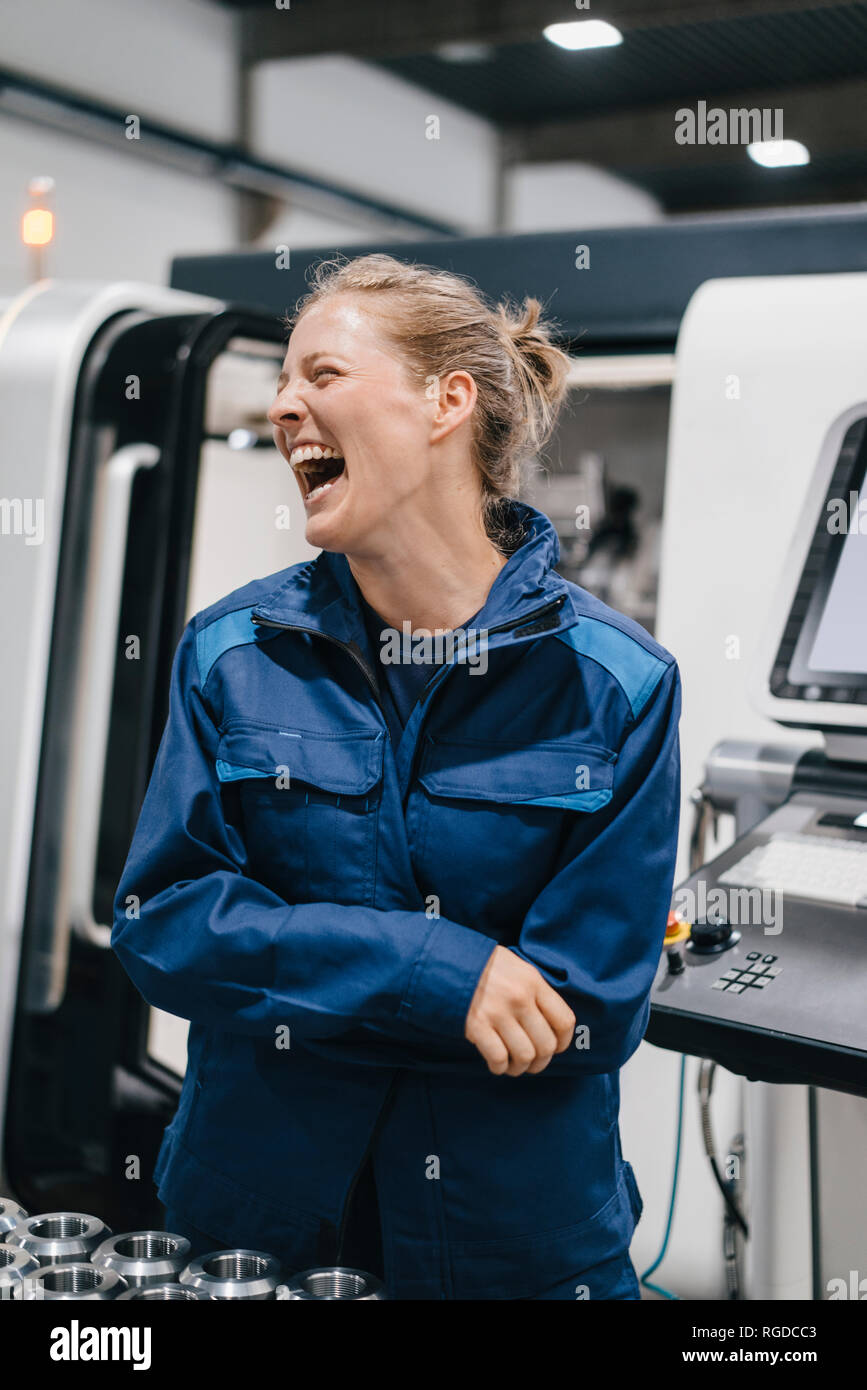 Giovane donna che lavora come un operaio specializzato in un high tech company, ridendo Foto Stock
