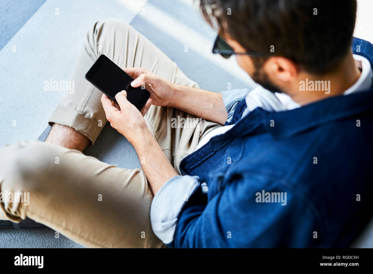 Giovane uomo seduto a terra per la messaggistica di testo Foto Stock