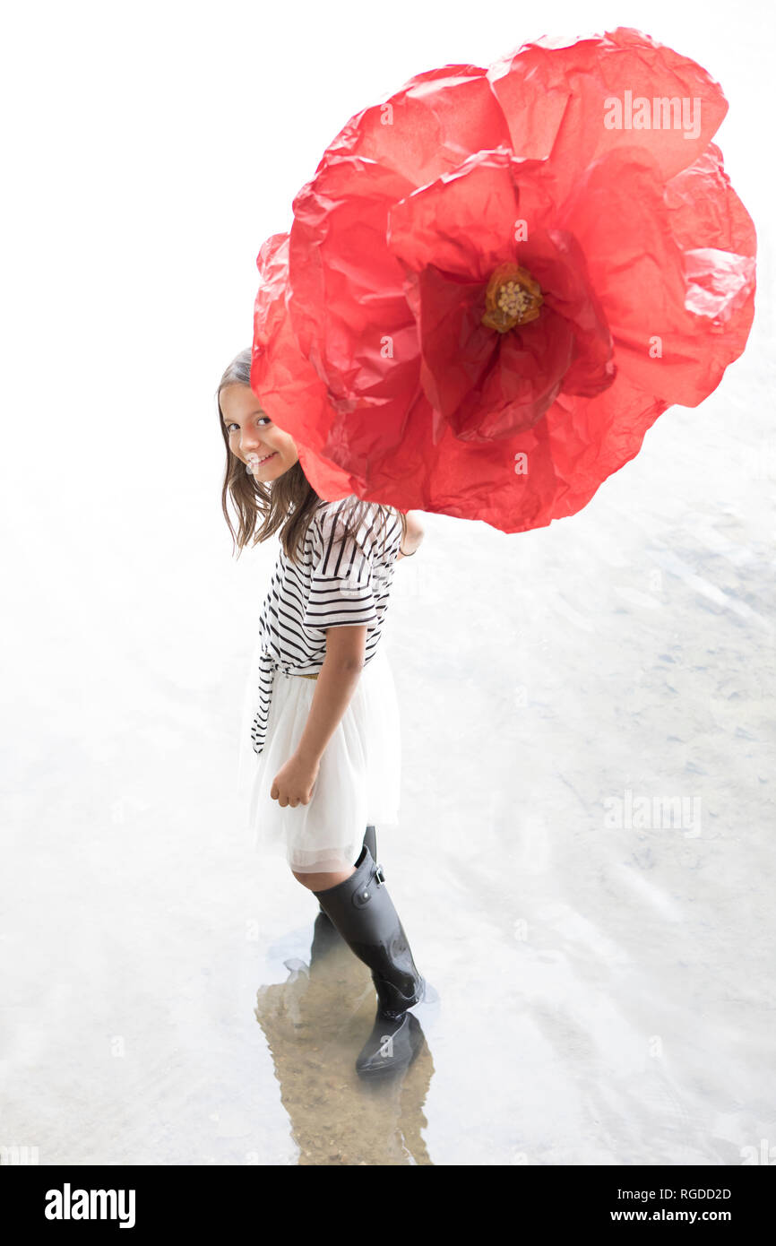 Ritratto di ragazza sorridente in piedi in un lago con grandi rosso Fiore artificiale Foto Stock