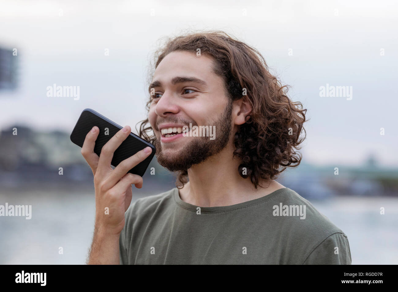 Ritratto di felice giovane uomo utilizza lo smartphone all'aperto Foto Stock