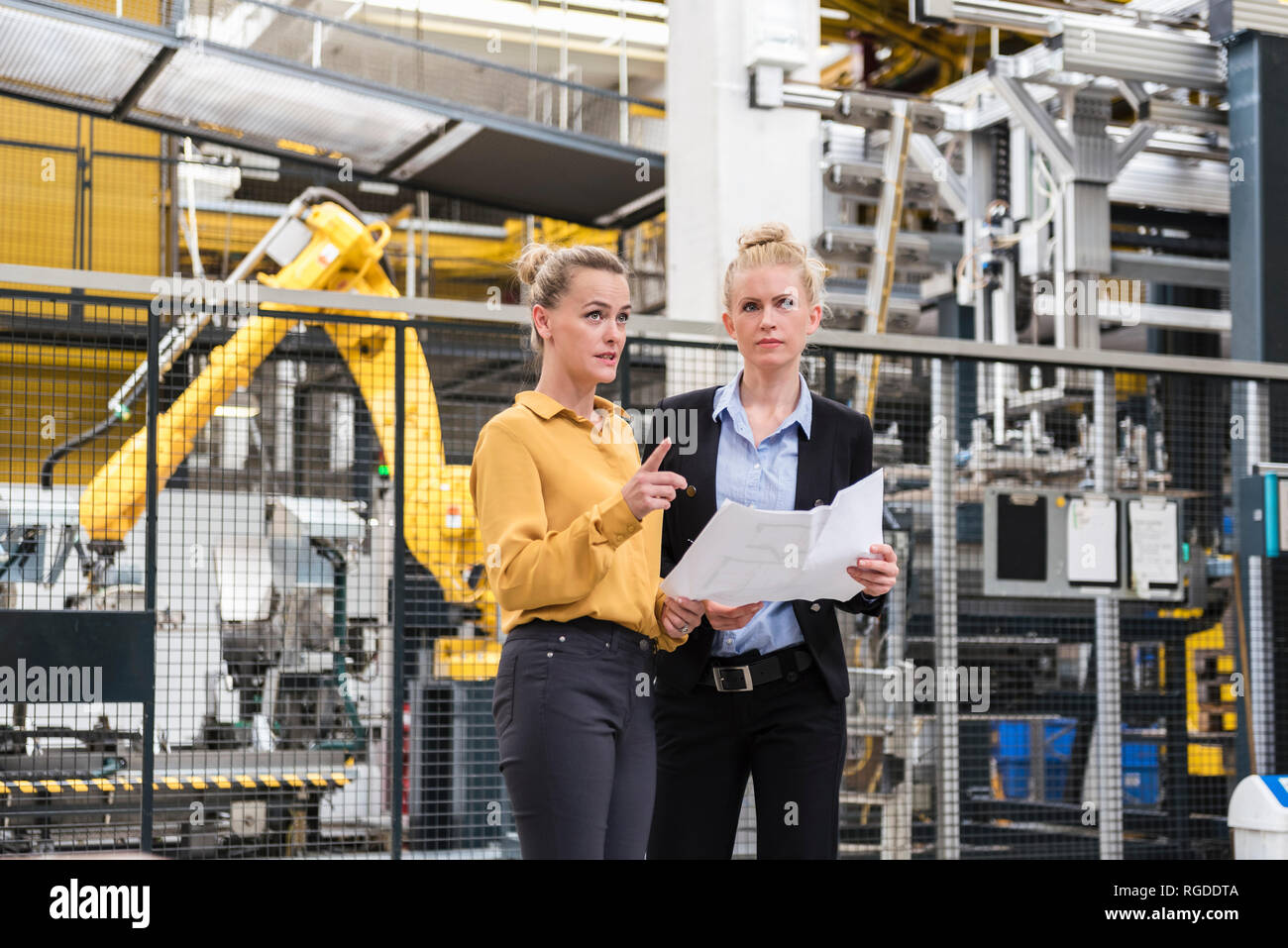 Due donne a discutere di piano in negozio della fabbrica piano con robot industriale Foto Stock