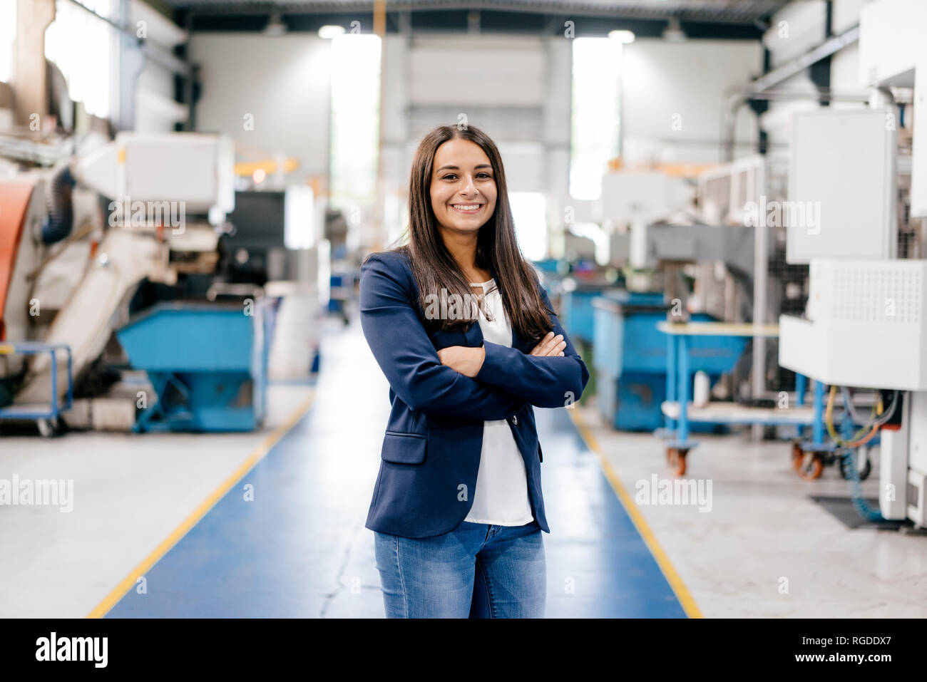 Fiducioso donna che lavorano in high tech enterprise, stando in officina in fabbrica con le braccia incrociate Foto Stock