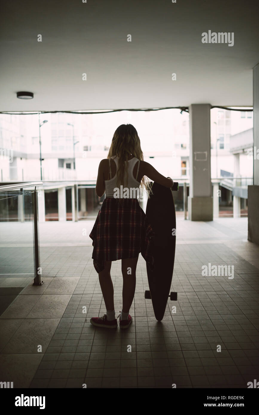 Giovane donna con il suo bordo lungo in una zona residenziale Foto Stock