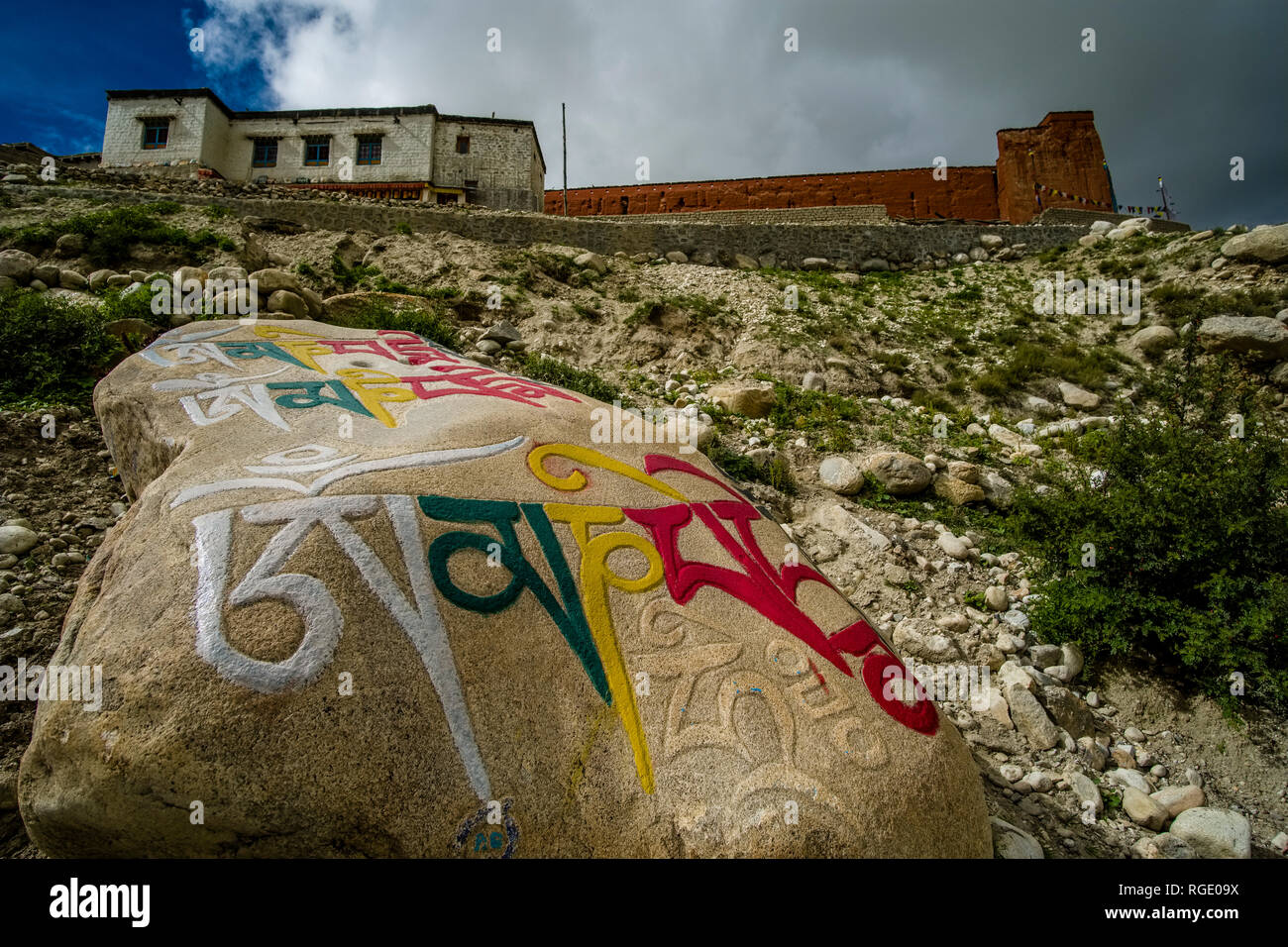 Grandi Mani di pietra con le rocce scolpite mantra buddista di Avalokiteshwara, OM MANI PADME HUM e le mura della città, scure nuvole monsoniche approachi Foto Stock