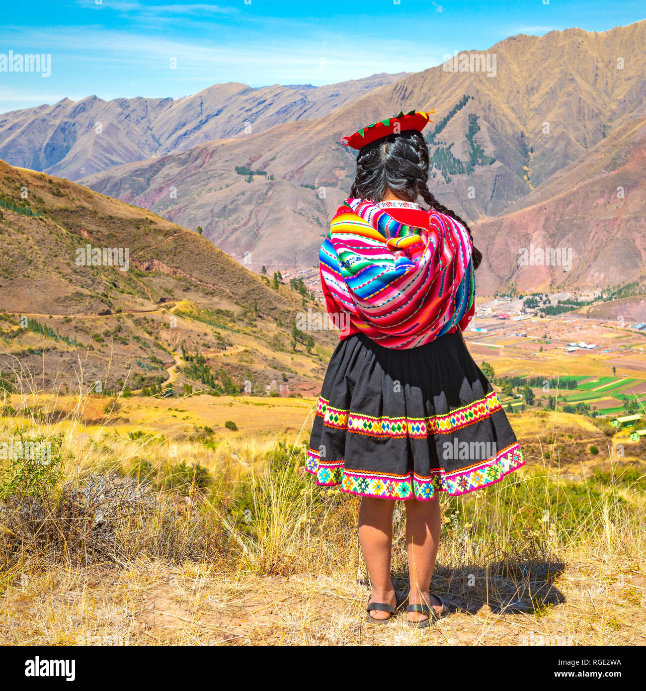 Formato quadrato di un indigeno Quechua lady in tradizionale stile di capelli, abito e hat guardando oltre la catena delle Ande in rovina Inca di Tipon, Perù. Foto Stock
