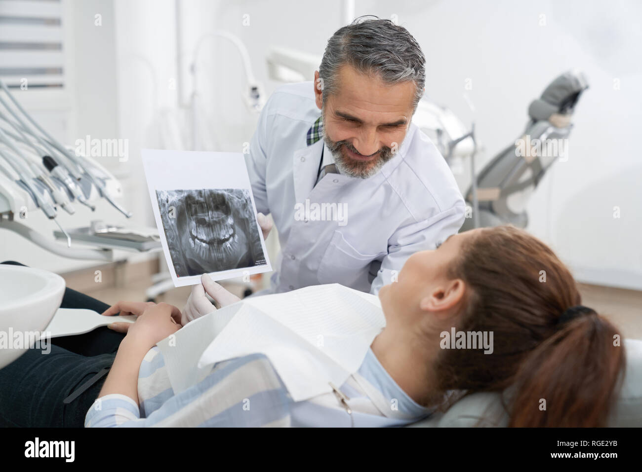 Stomatologia medico mostra apparecchiature odontoiatriche a raggi x della ganascia al paziente, consulting. Giovane donna sdraiata sulla poltrona del dentista, guardando a scansione. Concetto di Cura dei denti e Stomatologia. Foto Stock