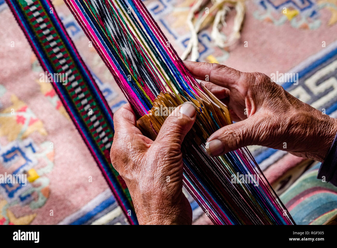 Le mani di una vecchia donna locale, la tessitura di una sciarpa colorata Foto Stock