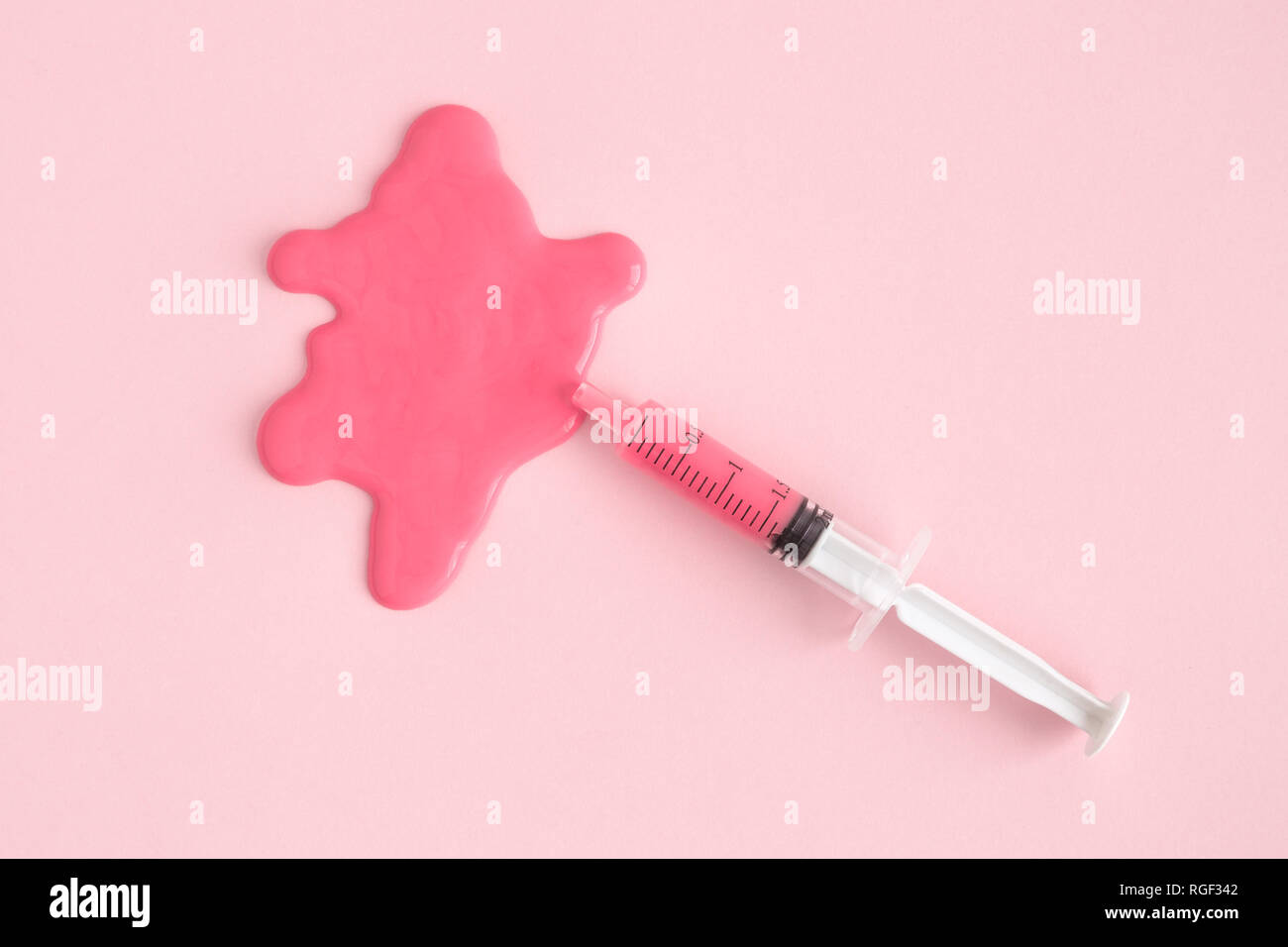 Angolo di alta vista della siringa e macchia contro di rosa pastello minima di sfondo concetto creativo. Foto Stock