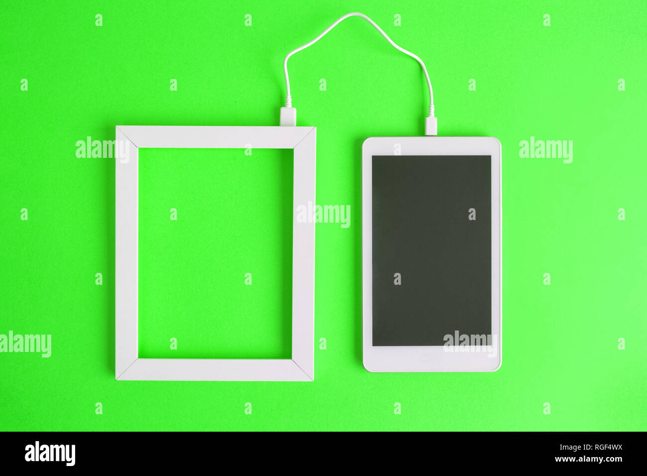 Piatto di laici photo frame e schermo vuoto digitale compressa dispositivo collegato con cavo isolato su sfondo verde. Il trasferimento dei dati minimi conce creative Foto Stock