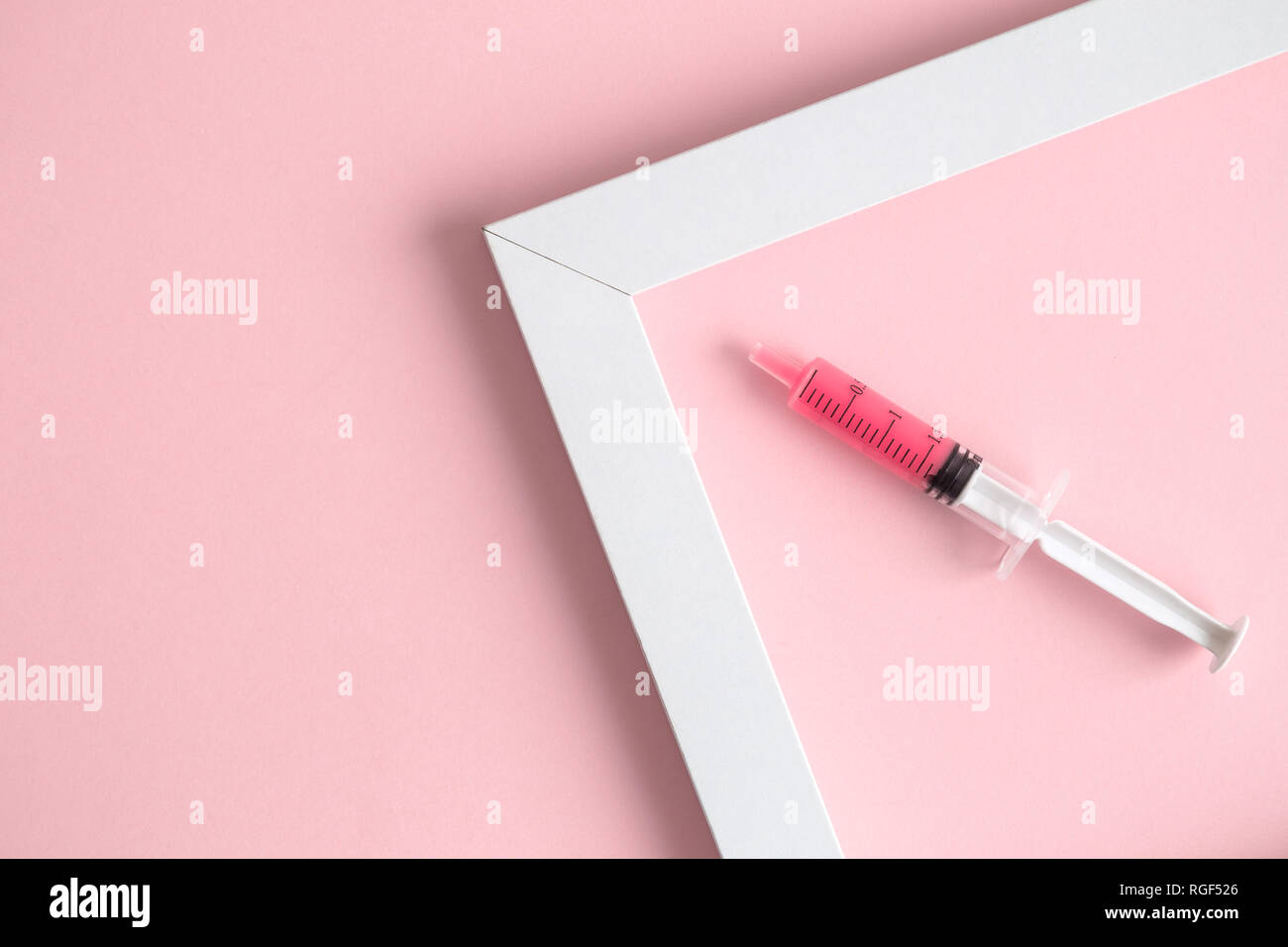 Piatto di laici la siringa e la cornice immagine isolata sul rosa pastello minima di sfondo concetto creativo. Foto Stock