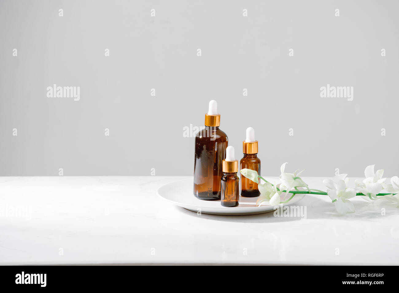 Impostazione di Spa con orchidee e olio essenziale in una bottiglia di vetro, aromaterapia concept Foto Stock