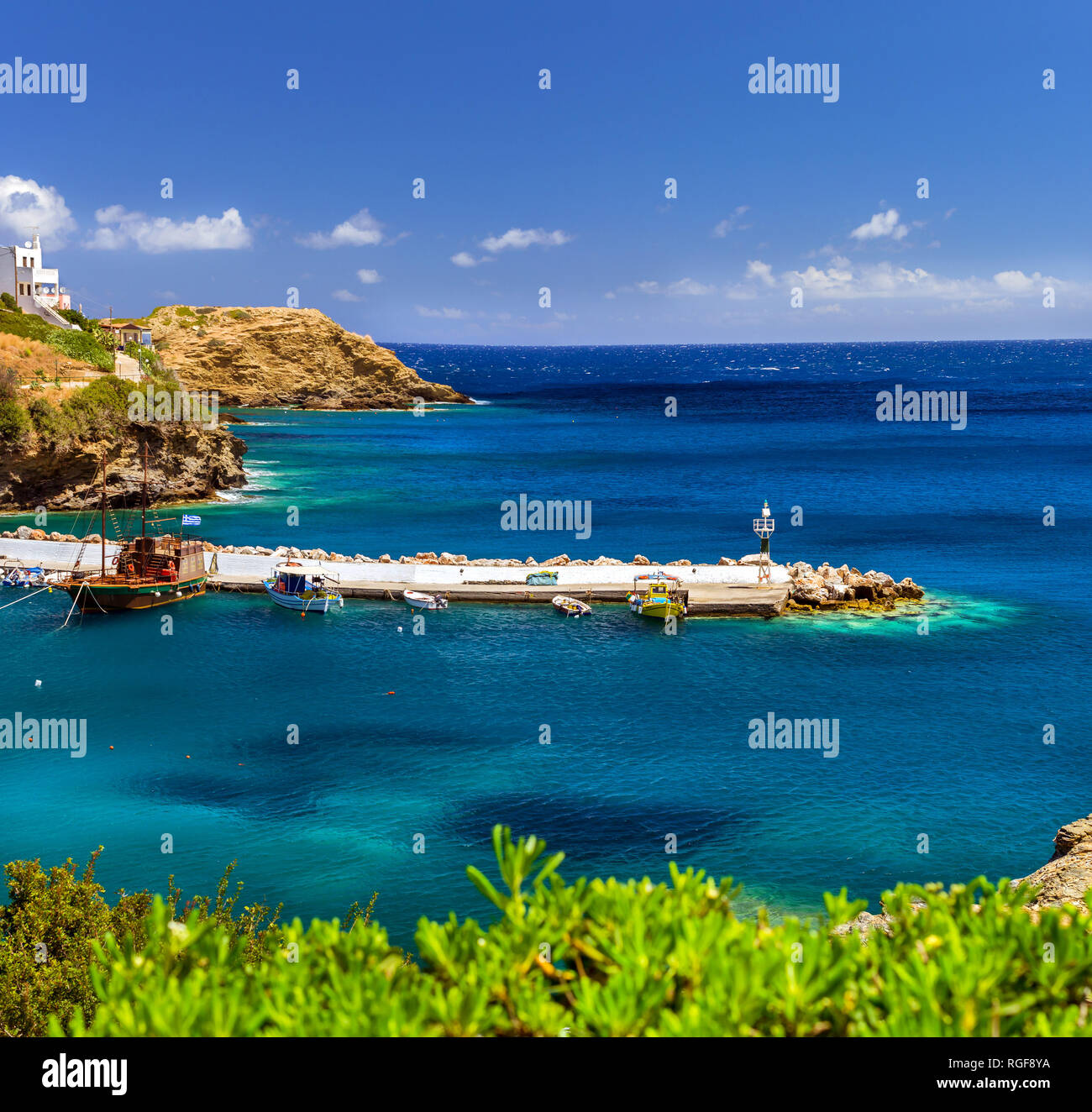 Porto con navi marine, barche e il faro. Vista dalla scogliera sulla baia con architettura Bali. Destinazione di vacanza balneare, con spiagge e turchese chiaro acque oceaniche, RETHIMNO, CRETA Grecia Foto Stock