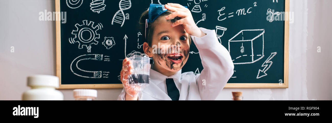 Ritratto di poco sorpreso di scienziato con faccia sporca tenendo il vetro con schiuma di sapone dopo un esperimento pazzo Foto Stock