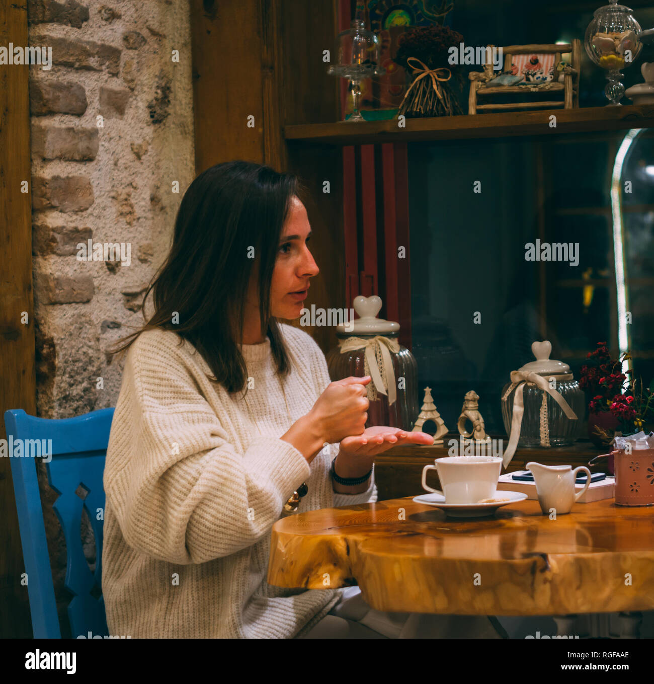 Giovane donna seduta nella caffetteria e parlare con il linguaggio dei segni. Esprimendo la farmacia. Foto Stock