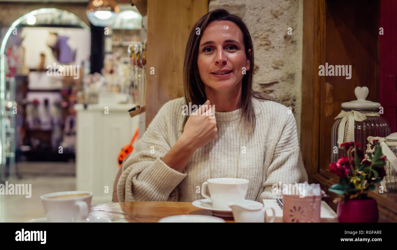 Bella donna seduta nella caffetteria e parlare con il linguaggio dei segni. Ritratto di signora esprimendo "operazione". Foto Stock