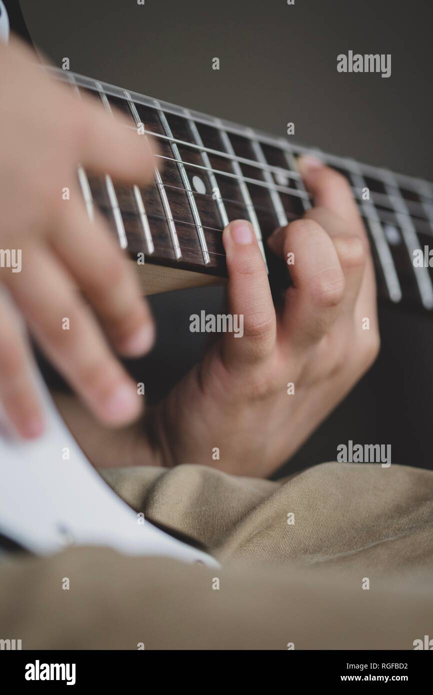 8 anno di età Inglesi Indian boy praticando la chitarra a casa. Foto Stock