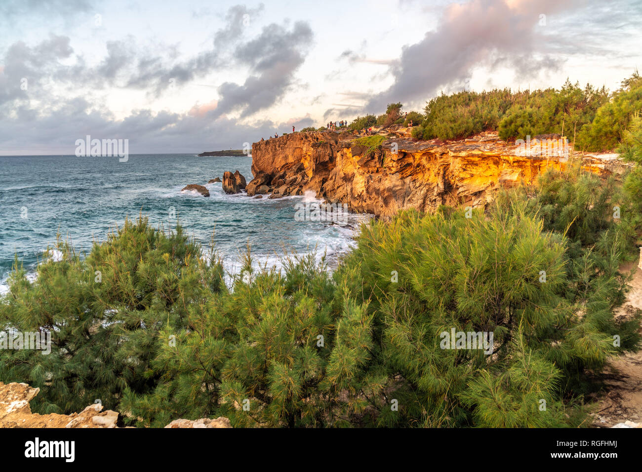 I visitatori si sono riuniti su una roccia a guardare il tramonto sull'oceano, Poipu, Koloa, Kauai, Hawaii Foto Stock
