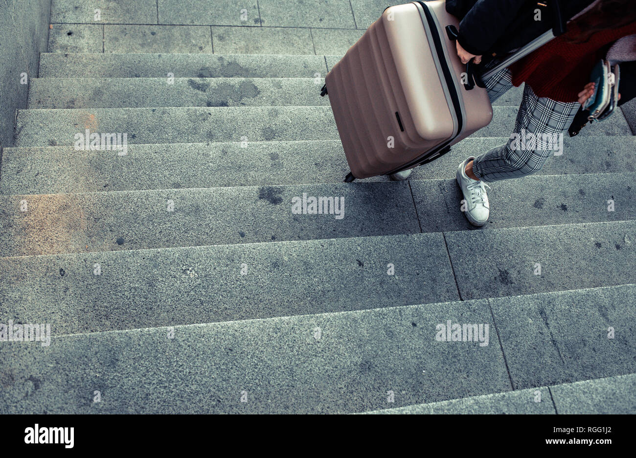 Donna trascinando una valigia trolley per salire le scale di una  metropolitana Foto stock - Alamy