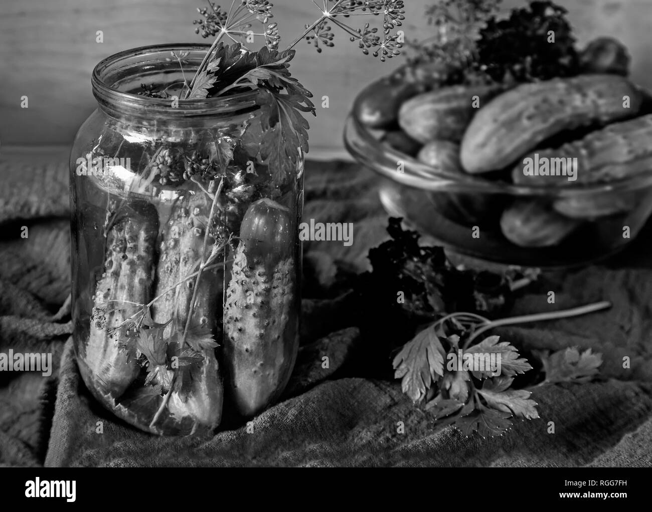 Sul tavolo i cetrioli, progettato per il decapaggio in vetro conto bancario e le necessarie spezie: aneto, prezzemolo, aglio, in bianco e nero imageens. Foto Stock