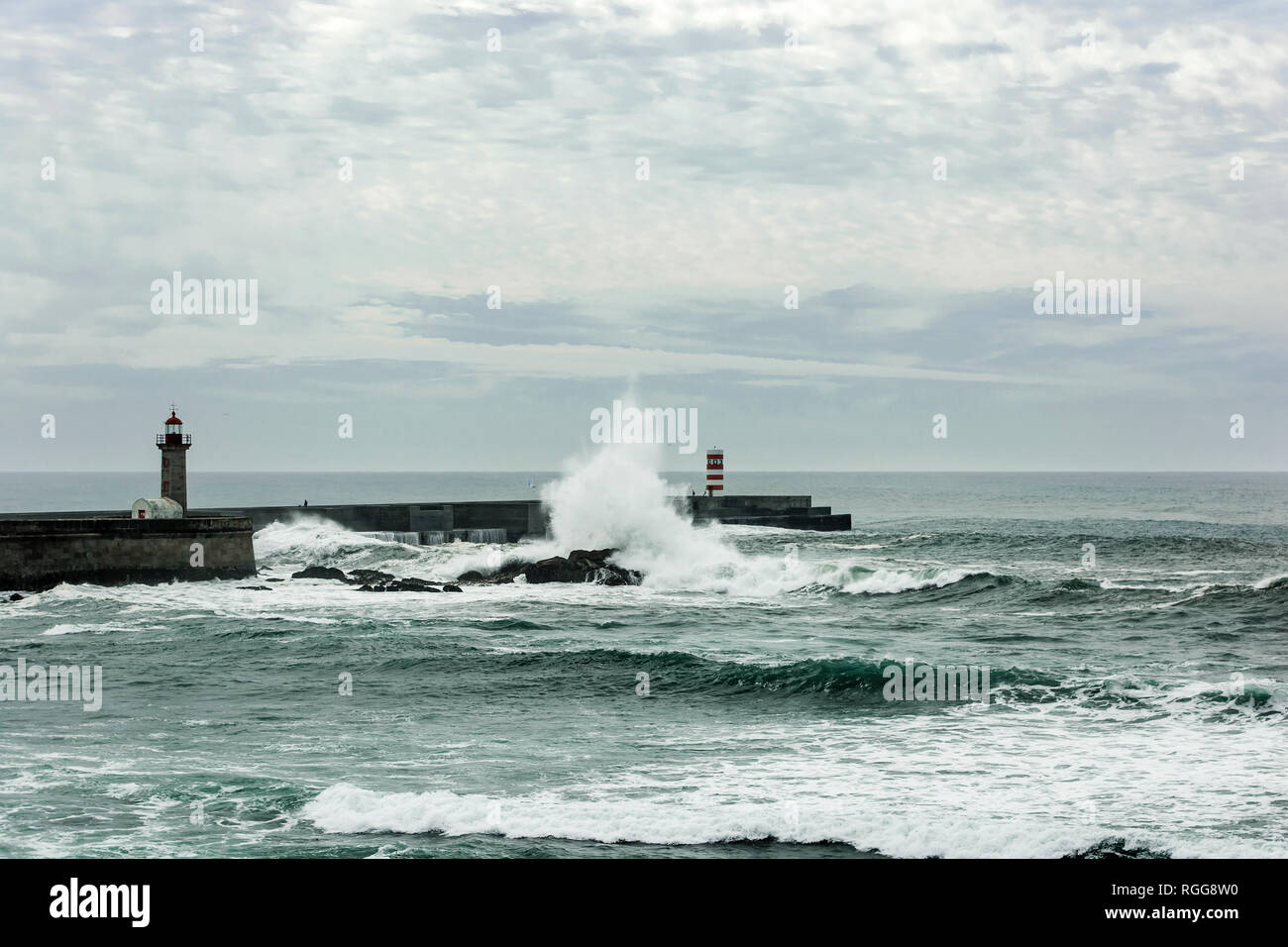 Mare tempestoso delle forme d'onda schiacciato su pier con il faro a Porto, Portogallo Foto Stock