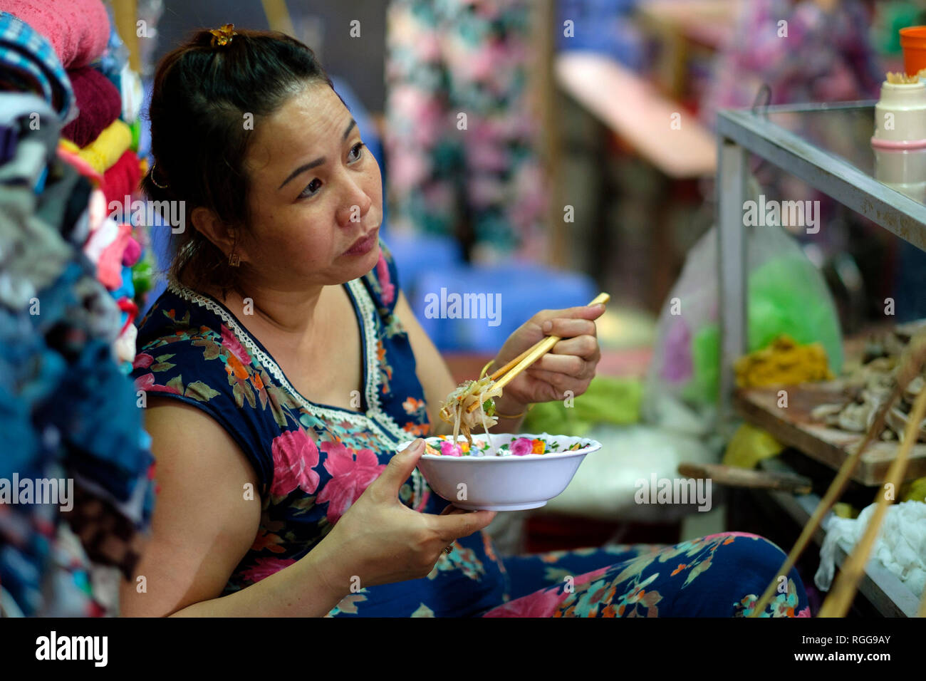 Donna di mangiare cibo di strada con bacchette di Dong Ba market in tinta, Vietnam, Asia Foto Stock