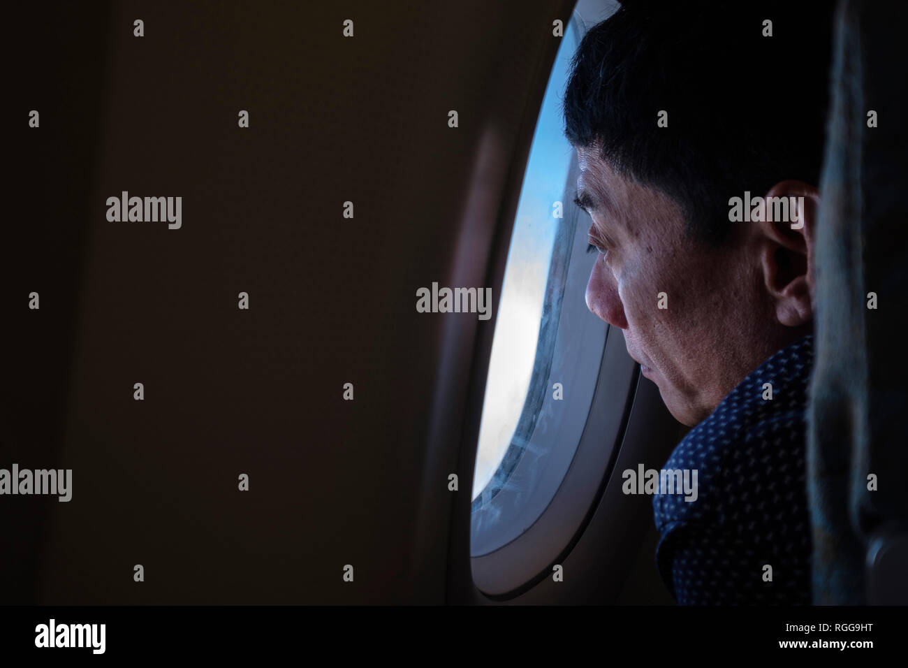 Uomo che guarda fuori dalla finestra di un aereo in volo Foto Stock