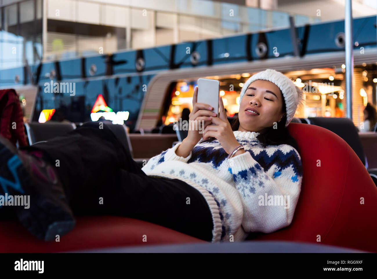 Ragazza con telefono mentre è in attesa presso la porta di aeroporto Foto Stock