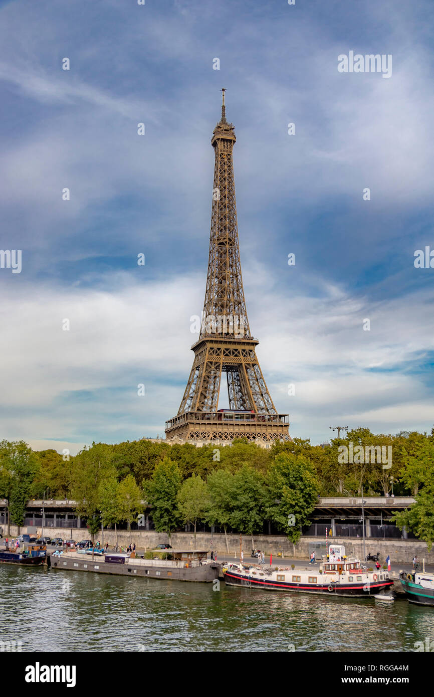 La Torre Eiffel sorge sopra il fiume Senna ,con barche in primo piano ormeggiate lungo la riva del fiume , Parigi Foto Stock