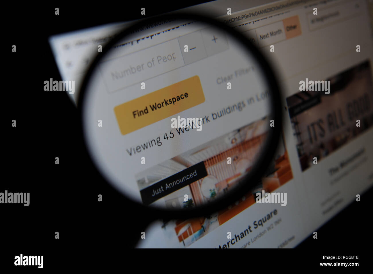 Il sito web wework visto ed espressiva attraverso una lente di ingrandimento sullo schermo di un computer Foto Stock