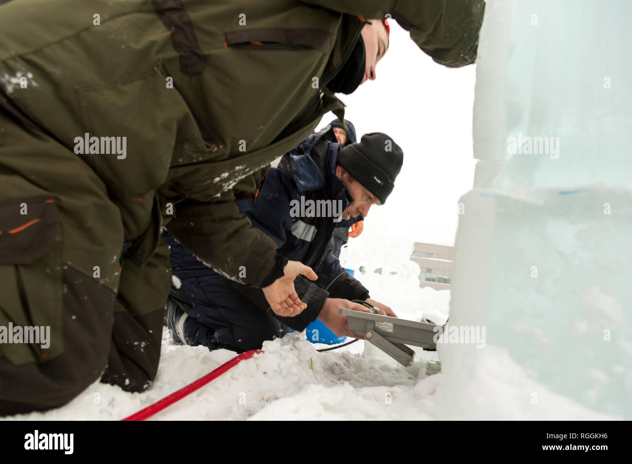 Elettricisti il montaggio di un cavo di alimentazione per illuminare le figure di ghiaccio. Foto Stock