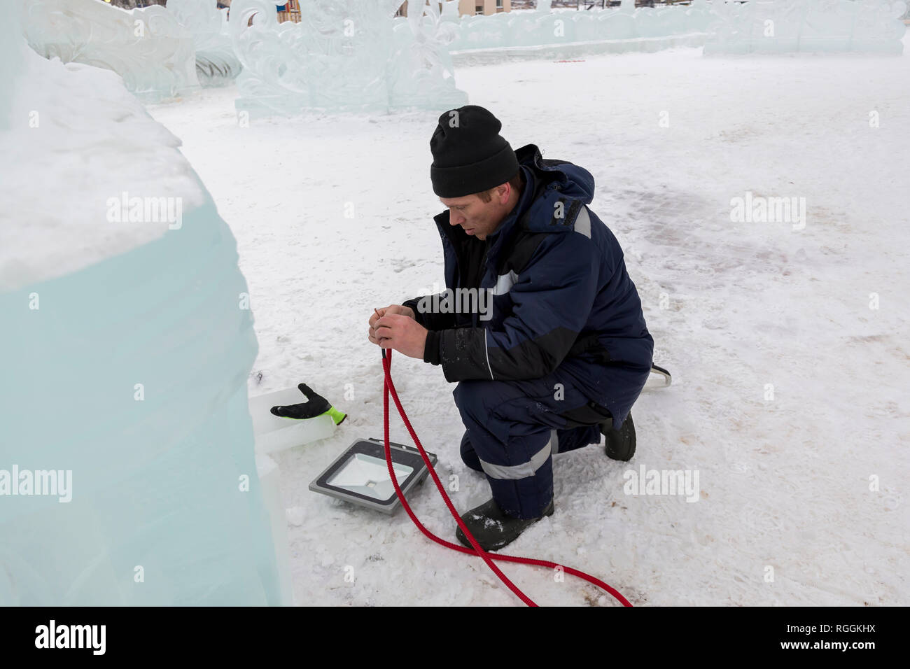 Elettricista pulisce le estremità del cavo di alimentazione per illuminare le figure di ghiaccio Foto Stock