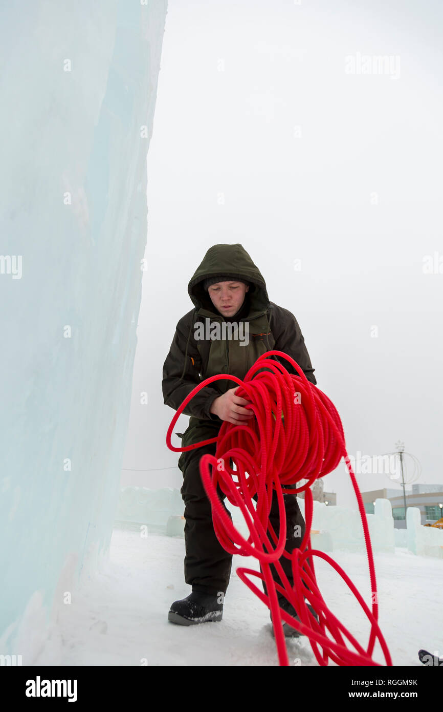 Elettricista si monta il cavo di alimentazione per illuminare le figure di ghiaccio. Foto Stock