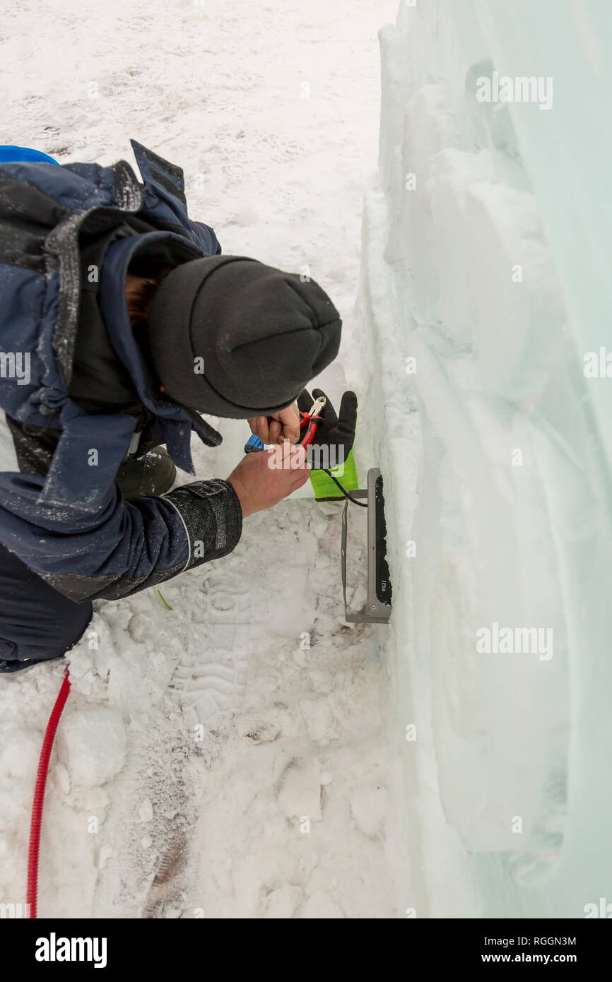 Elettricista monta torcia LED per illuminare la figura di ghiaccio Foto Stock