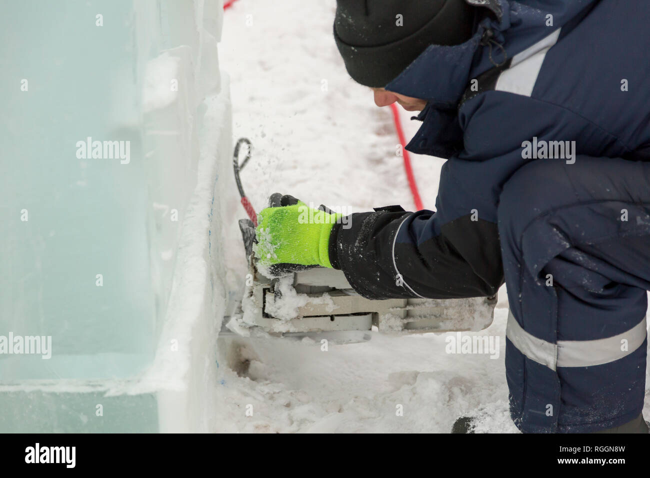 Il programma di installazione interrompe una nicchia con un chainsaw sotto la lampada a LED per illuminare la figura di ghiaccio Foto Stock