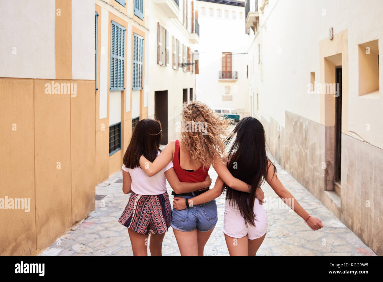 Spagna, Mallorca, Palma, vista posteriore di tre giovani donne a piedi nella città che abbraccia ogni altro Foto Stock