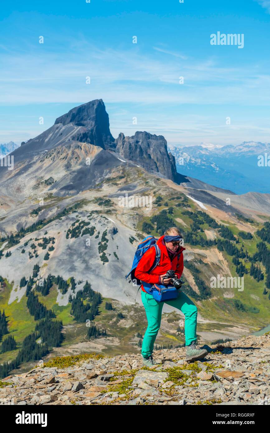 Escursionista sul sentiero escursionistico Panorama Ridge, piccoli laghi di fronte montagne, montagna vulcanica nero brosmio, Garibaldi Provincial Park Foto Stock