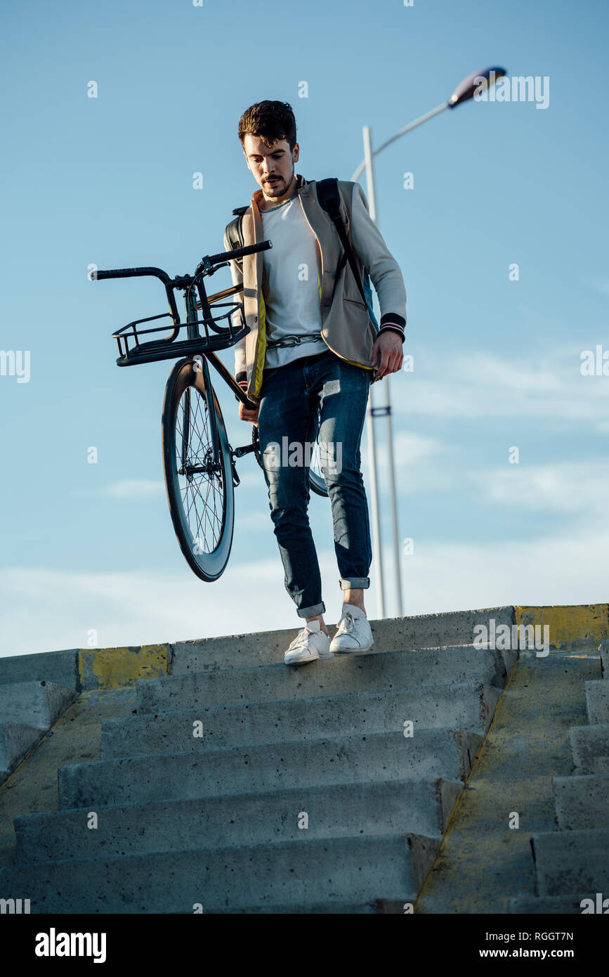 Giovane uomo che porta commuter fixie bike a piedi giù per le scale Foto Stock