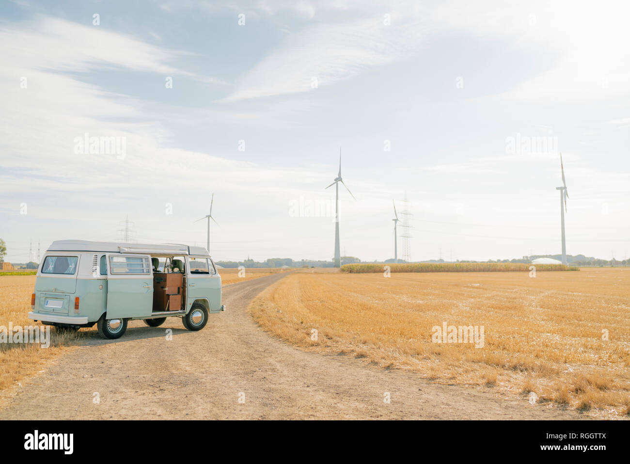 Camper parcheggiato su sterrato nel paesaggio rurale con turbine eoliche Foto Stock