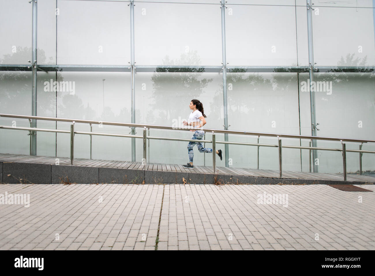 Giovane donna che corre lungo edificio della città Foto Stock