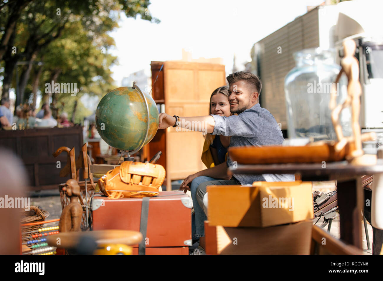 Belgio, Tongeren, coppia giovane esaminando globe su un antico mercato delle pulci Foto Stock