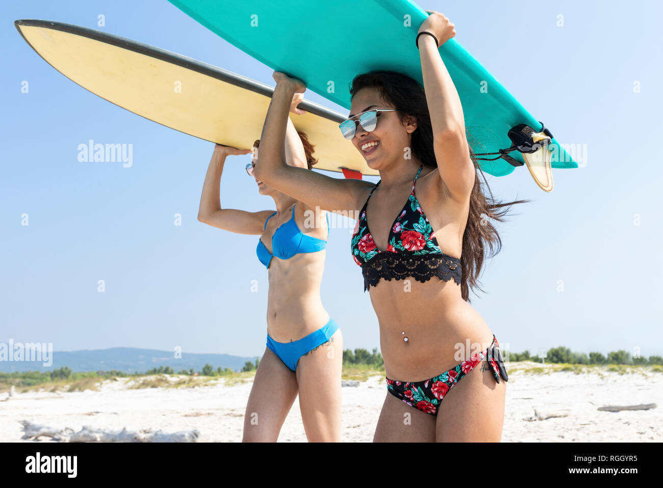 Gli amici di andare a fare surf, portando le tavole da surf sulla parte superiore delle teste Foto Stock