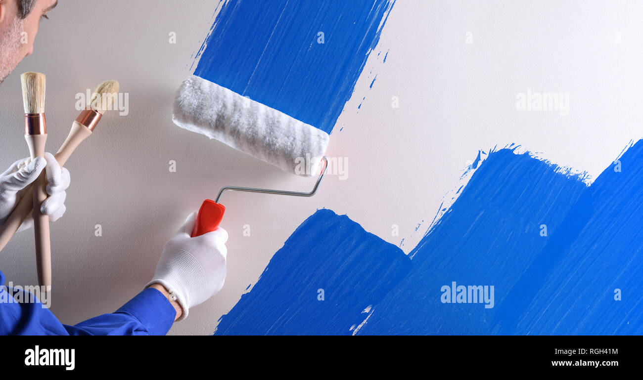 Concetto di pittore parete di verniciatura con vernice blu. Composizione orizzontale. Foto Stock
