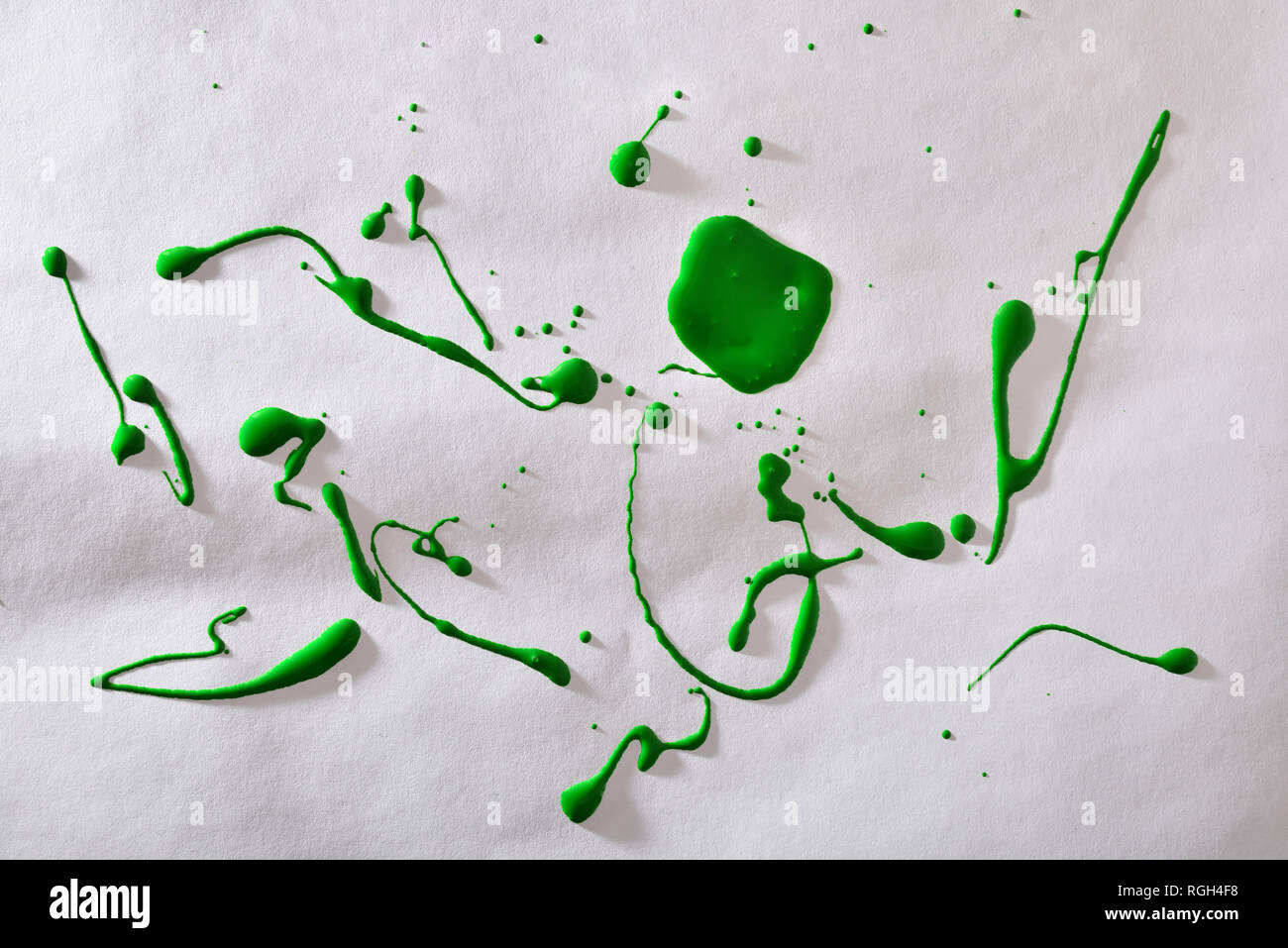 Vernice verde a gocce su bianco a trama lo sfondo della carta. Composizione orizzontale. Foto Stock