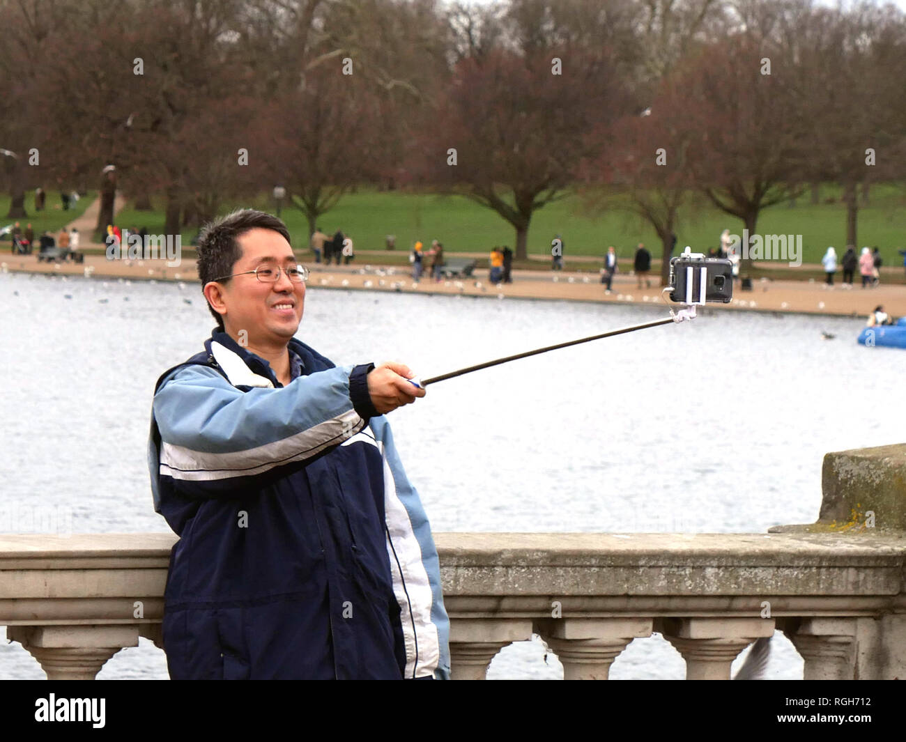 Oriental uomo prendendo selfie sul ponte a Hyde Park, Londra UK. Foto Stock