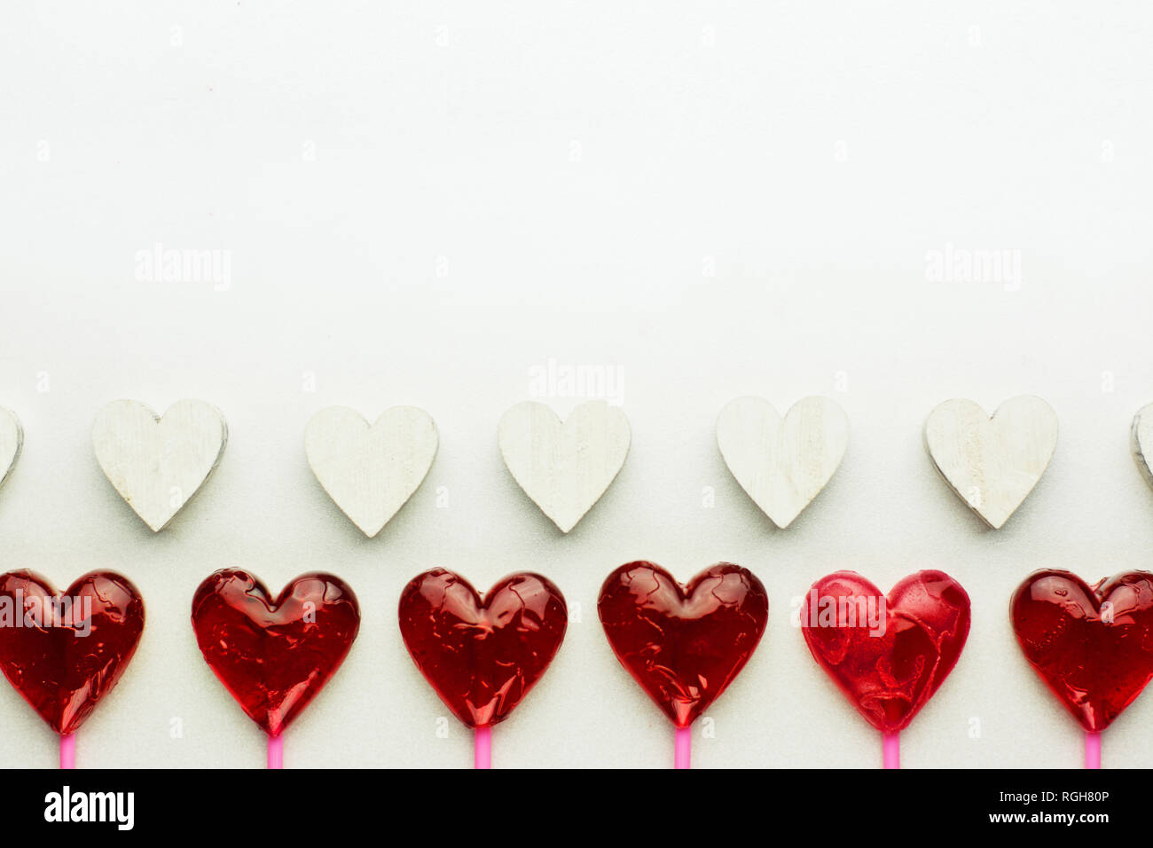 Modello di San Valentino con due righe di cuori - rosso lecca-lecca cuore bianco e cuori di legno Foto Stock