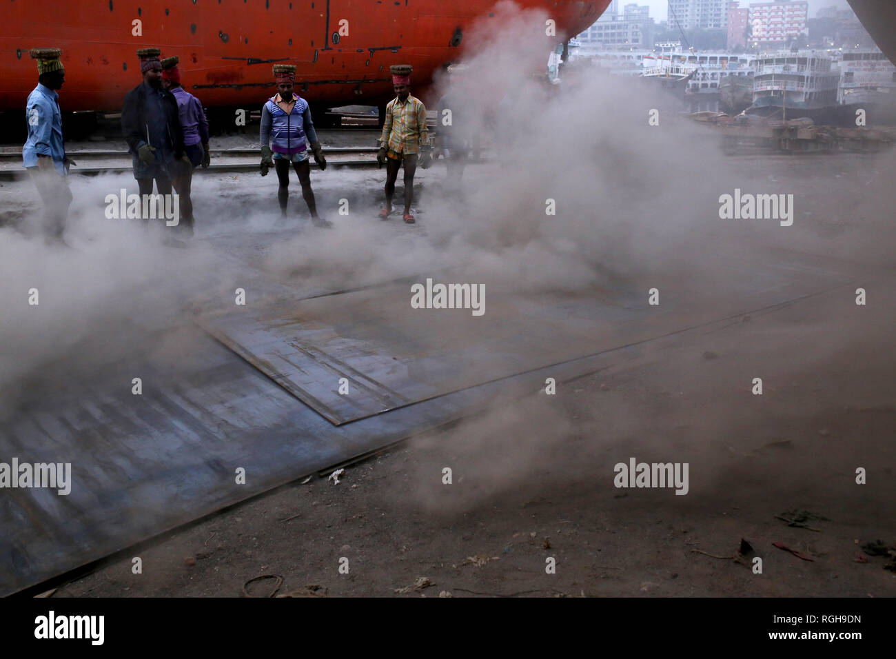 Lavoratori portano una pesante pezzo di lamiera in un cantiere navale a Dhaka, nel Bangladesh il 29 gennaio 2019. Decine di cantieri che occupa 30.96 acri del Buriganga foreshore sono state in funzione per gli ultimi cinquant'anni. Essa è principalmente utilizzata per il fissaggio e la riparazione di navi vecchie, costruire in nuove navi. Fatiche lavori in cantiere senza caschi, la maschera per il viso o scarpe di sicurezza come la loro età da 8 a 80 anni di età. Quasi 15.000 fatiche compresi i bambini lavorano in questo cantiere dall alba al tramonto come essi pagato circa $5 ogni giorno. © Rehman Asad / Alamy Stock Photo Foto Stock