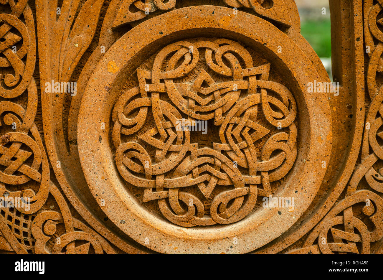 Oshakan,Armenia,19 Februar,2018:Round cornice scolpita su una pietra rossa con un ornamento di strisce intrecciate formano una croce al centro Foto Stock