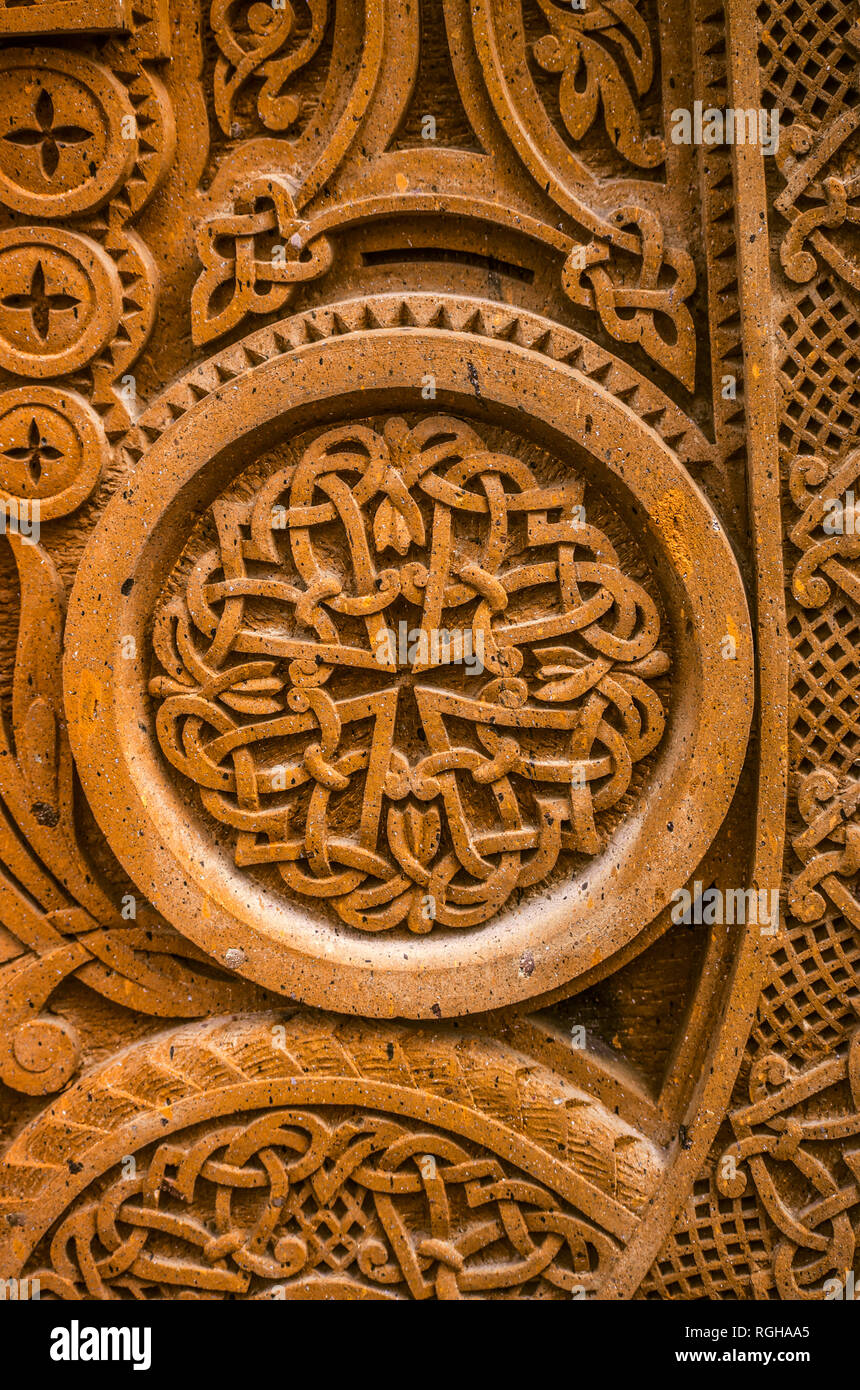 Oshakan,Armenia,19 Februar,2018:Round ornamento con intreccio pattern di strisce incise poste in una cornice rotonda su un rosso di pietra vulcanica Foto Stock