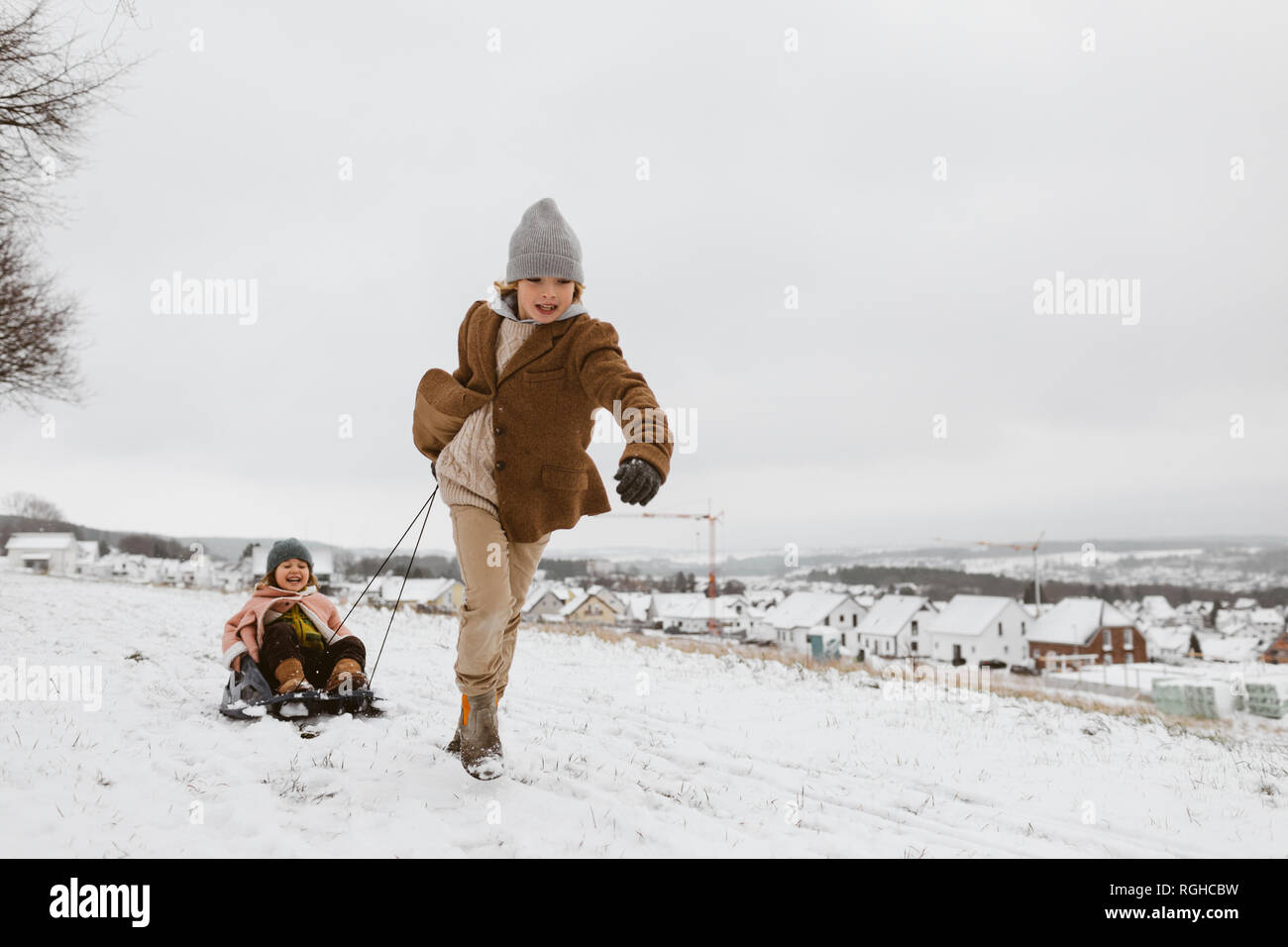 Ragazzo tirando la slitta con piccola sorella nella neve Foto Stock